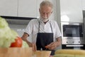 Elderly man standing at kitchen counter with colorful fresh vegetables, fruits and food ingredients, senior man preparing for Royalty Free Stock Photo