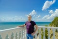 An elderly man stands near a white fence with balusters and looks at the blue sea Royalty Free Stock Photo