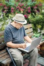 Elderly man in a straw hat is working on a laptop and enjoying life, smiling happily. An old man with a mustache gestures that Royalty Free Stock Photo