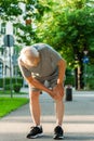 Elderly man suffering from knee pain during his jogging workout Royalty Free Stock Photo