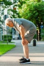 Elderly man suffering from knee pain during his jogging workout Royalty Free Stock Photo