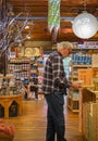 Elderly man at supermarket. Shoppers at grocery store defocused. People walking at day market