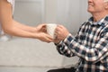 Elderly man taking cup of tea from female caregiver Royalty Free Stock Photo