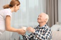 Elderly man taking cup of tea from female caregiver Royalty Free Stock Photo