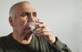 Elderly man taking medication with water in a close up portrait Royalty Free Stock Photo
