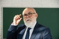 Elderly man teacher on a blank chalkboard during lesson, teaching class at college. Think senior. Teachers day. Royalty Free Stock Photo