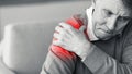 Elderly Man Touching Aching Shoulder Sitting On Sofa Indoor, Black-And-White Royalty Free Stock Photo