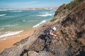 Elderly man trying to climb a rock to the top of a mountain on a sunny day in the Odemira region, western Portugal. Wandering