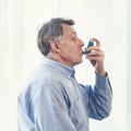 Elderly man using asthma inhaler for allergies Royalty Free Stock Photo