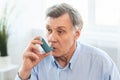 Elderly man using asthma inhaler for allergies Royalty Free Stock Photo