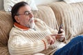 Elderly Man Using Cellphone Sitting On Sofa At Home, during Coronavirus quarantine.