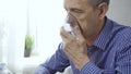 An elderly man is using an inhaler. Treatment of airway inflammation with a nebulizer. Close-up. Royalty Free Stock Photo