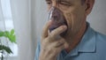 An elderly man is using an inhaler. Treatment of airway inflammation with a nebulizer. Close-up. Royalty Free Stock Photo