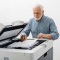 Elderly man using a multifunction printer to scan documents in an office setting Royalty Free Stock Photo