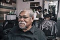 An elderly man waits in a barbers chair for his haircut