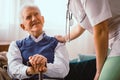 Elderly man with stick being comforted by doctor in nursing home