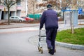 Elderly man walking with a wheeled walker on an empty street in autumn