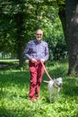 Elderly Man is Walking a White Pitbull Terrier Dog in the Park