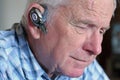 Elderly man wearing hands-free cell phone device Royalty Free Stock Photo