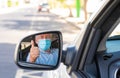 Elderly man wearing a protective mask while driving the car looking at the camera in the mirror Royalty Free Stock Photo