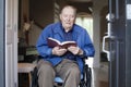 Elderly man in wheelchair reading the Bible