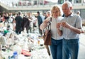 Elderly man and woman consider things in flea market Royalty Free Stock Photo