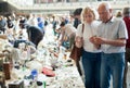 Elderly man and woman consider things in flea market
