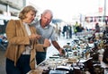 Elderly man and woman consider things in flea market