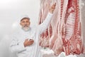 Man in uniform standing near row of pork carcasses, testing. Royalty Free Stock Photo