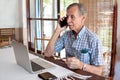 An elderly man works using a laptop office at home.