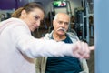 Elderly man worming up at gym with female trainer Royalty Free Stock Photo