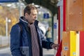 An elderly man 45-50 years old buys a ticket at a ticket vending machine on the platform of the railway station