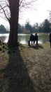 Elderly men sitting on a bench beside a lake reminiscing memories on a summer day Royalty Free Stock Photo