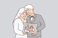Elderly men and woman in wedding clothes hold portrait of young couple from marriage ceremony