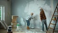 Elderly man and woman are painting wall with white paint using paint rollers. Couple of pensioners are making repairs to Royalty Free Stock Photo