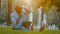 Elderly middle-aged African American businessman entrepreneur man sitting on grass in city park working on computer Royalty Free Stock Photo