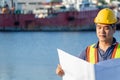 Elderly ,Middle - aged asians man engineer with yellow helmet and blue shirt is watching the project in the sheet near the