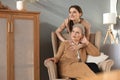 Elderly middle mother sitting in a chair and her daughter are hugging, looking away, trusted relations