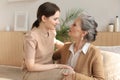 Elderly middle mother sitting on couch with joy holding adult daughter on knees. Happy trusted relations. Family concept