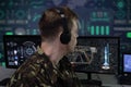 An elderly military man with headphones looks at the monitor against the background of a world map in the military center. Concept Royalty Free Stock Photo