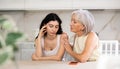 Elderly mother asks for forgiveness from her adult daughter and calms her down after a domestic quarrel in kitchen