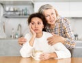 Elderly mother calms her daughter down and asks her for forgiveness after a domestic quarrel in kitchen