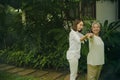 An elderly mother exercises in the morning with her daughter in the garden at home, cared for by her daughter.