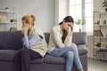 Elderly mother and grown up daughter after quarrel sitting on couch separately