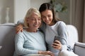 Elderly mother and grown up daughter using smartphone making selfie