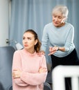 Elderly mother reprimanding frustrated girl sitting on sofa