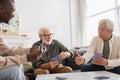 Elderly multiethnic men playing cards in Royalty Free Stock Photo
