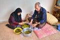 An elderly muslim couple is cooking food at home.