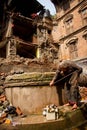 A elderly Nepali lady uses a well amongst the earthquake ruins i Royalty Free Stock Photo