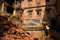 A elderly Nepali lady uses a well amongst the earthquake ruins i Royalty Free Stock Photo